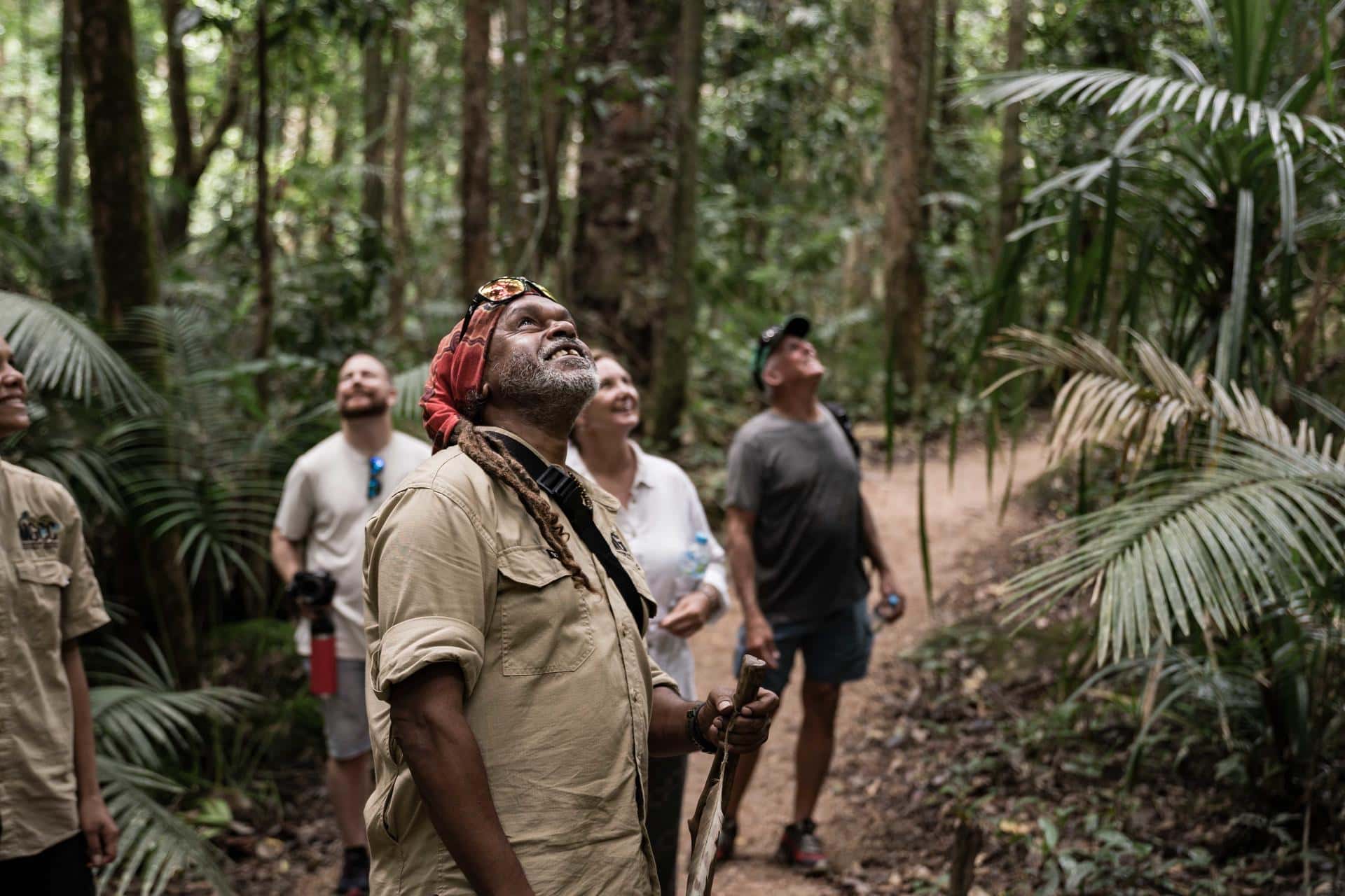 A Mossman Gorge guide offers insights into ancient traditions to visitors, standing under the rainforest canopy